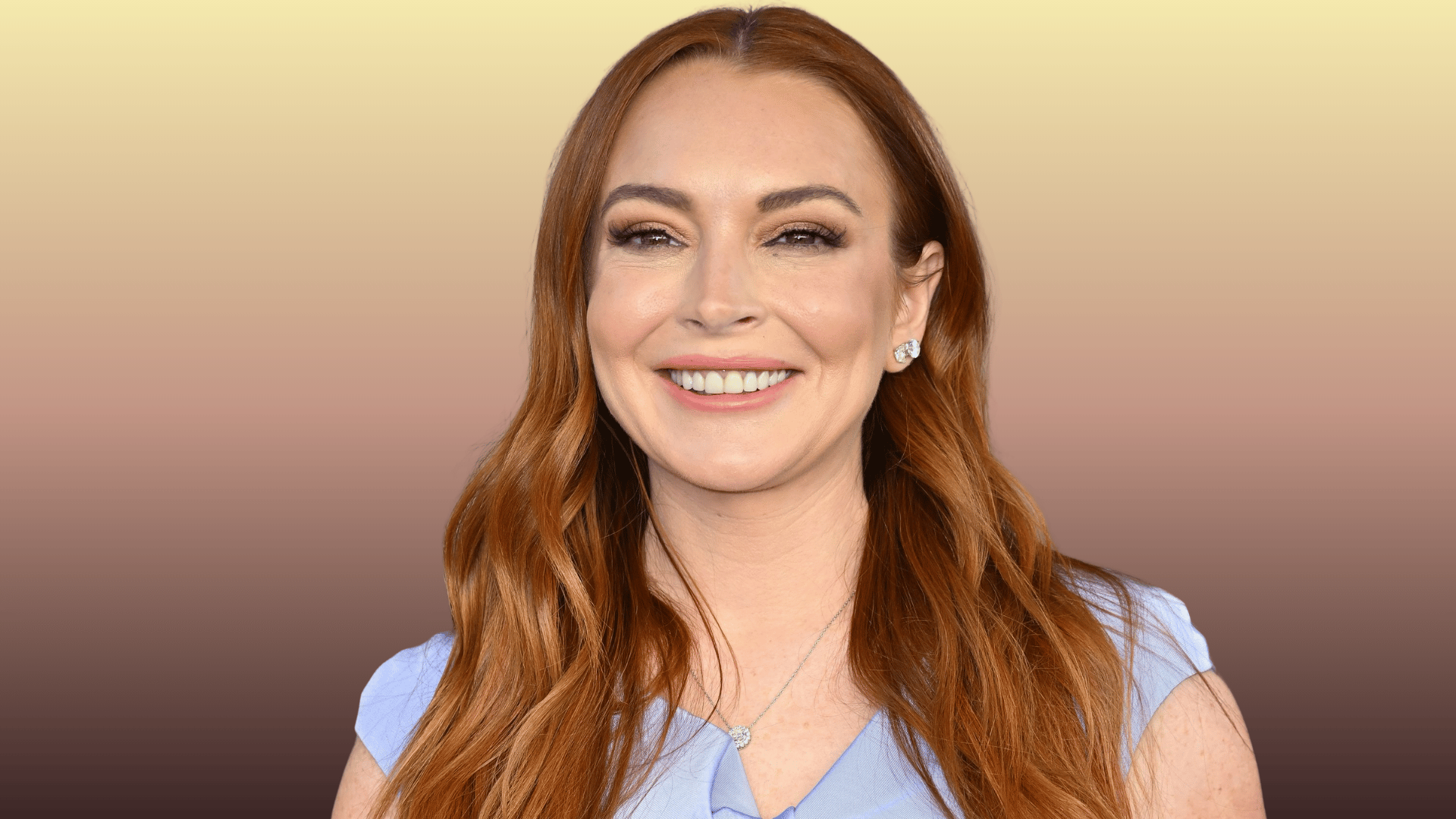 Lindsay Lohan smiling in a light blue outfit against a neutral background
