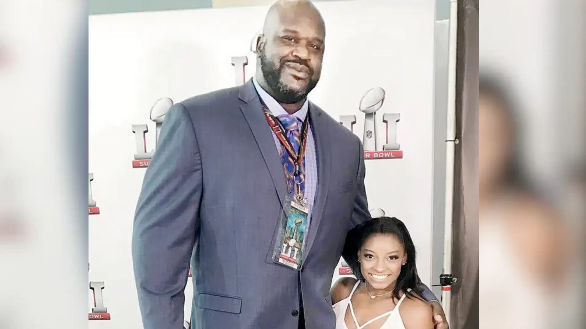 man and woman posing together at a super bowl event with event badges and a branded backdrop outside