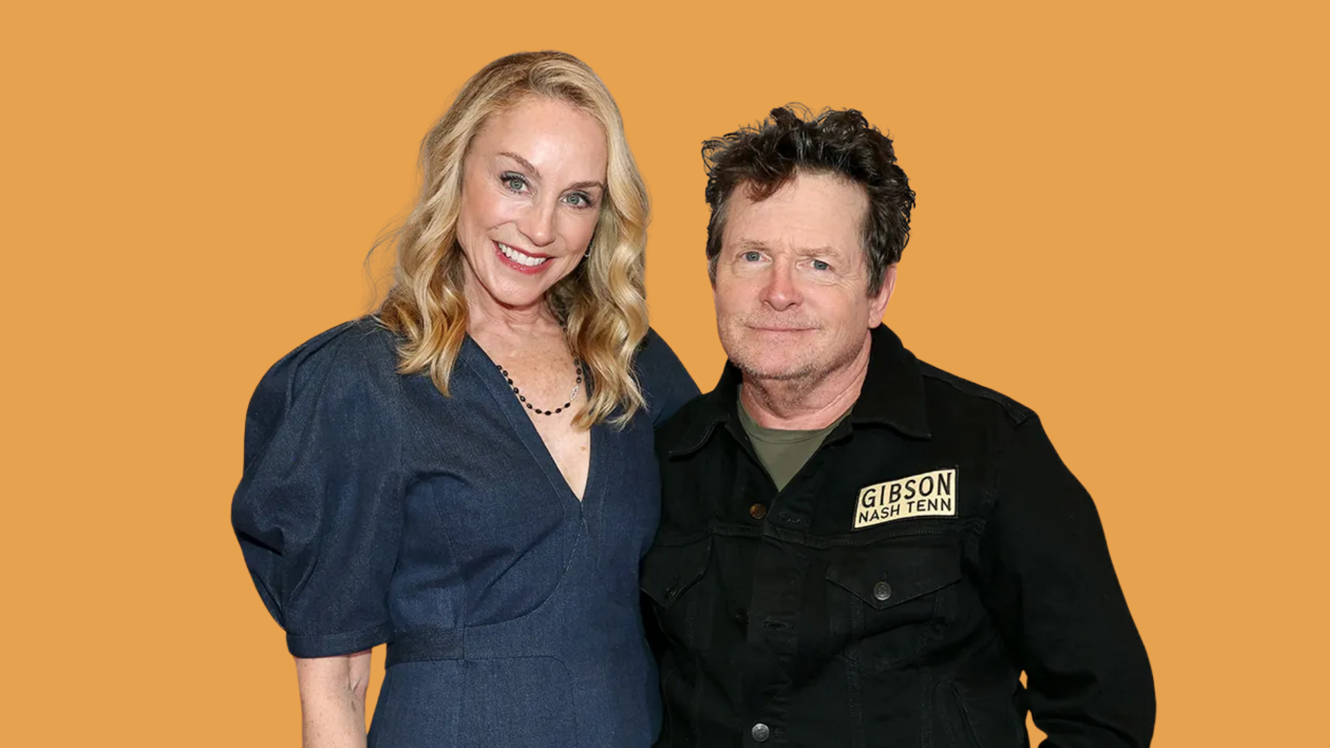 michael j. fox and his wife tracy pollan smiling together at an event, orange background
