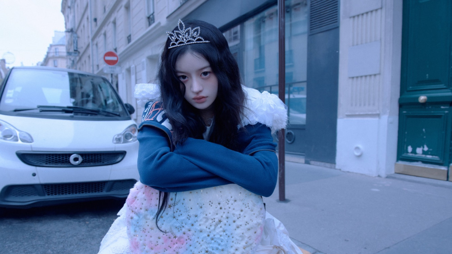 minju of illit wearing a tiara on a city street