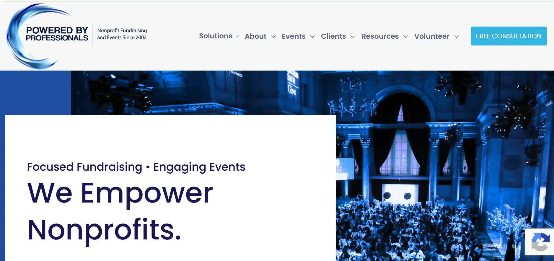 Large crowd gathered in elegant hall with blue lighting and chandeliers