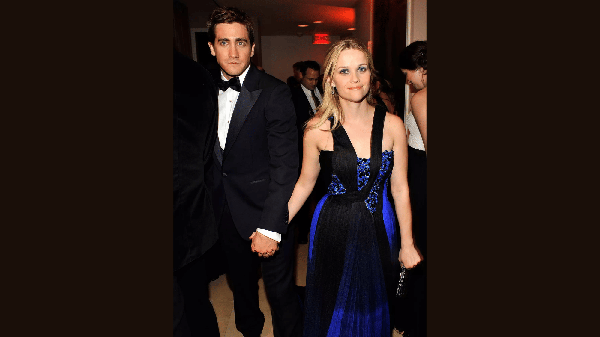 reese witherspoon holding hands with jake gyllenhaal while posing together in formal evening wear at an event