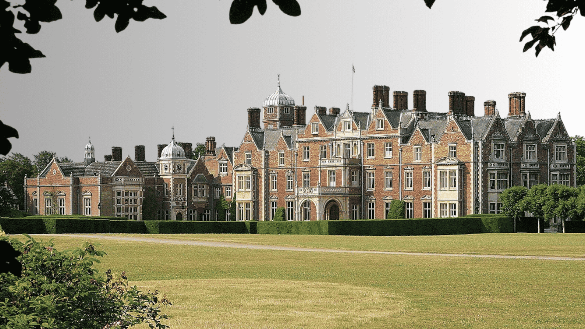 Sandringham House surrounded by lawns, hedges, and trees in Norfolk