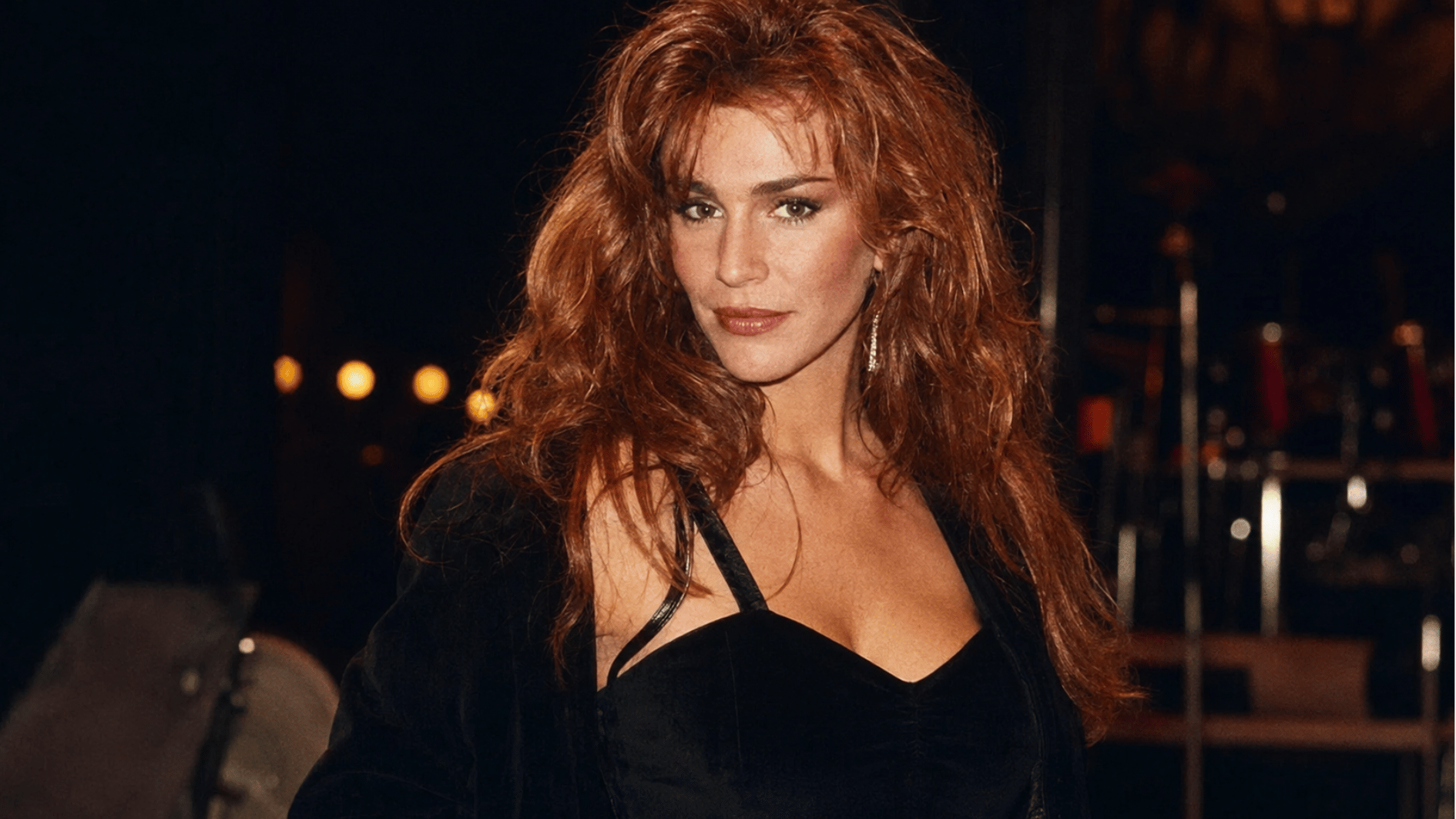 tawny kitaen posing at a night event with red hair and a black outfit