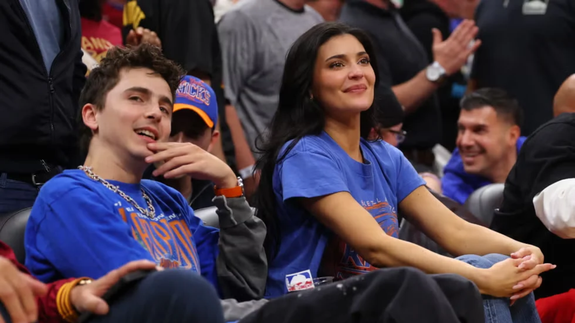 timothee chalamet and kylie jenner sitting courtside at a basketball game wearing matching blue shirts