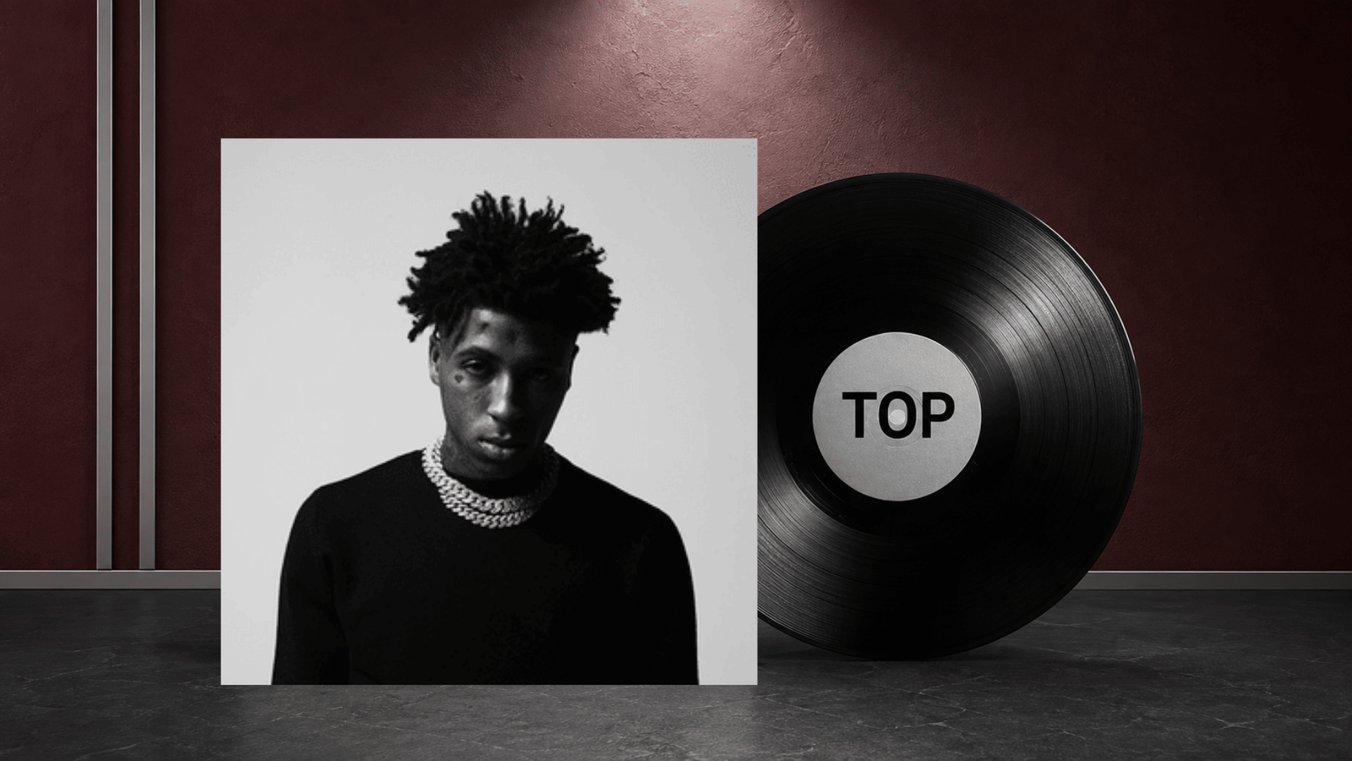 top album cover portrait beside a black vinyl record on a burgundy set