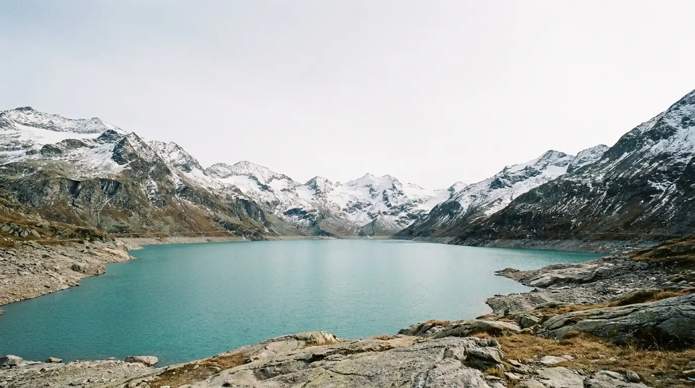 Snow-covered mountains surrounding a serene turquoise lake under a clear sky