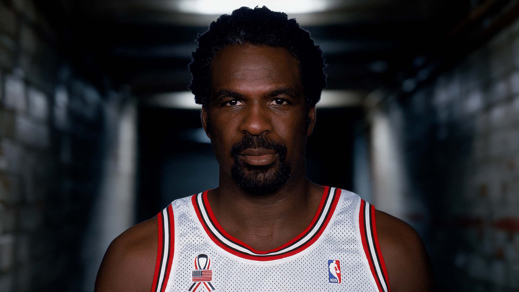 basketball player headshot showing charles oakley in a white jersey against a plain background with a focused expression and sharp details