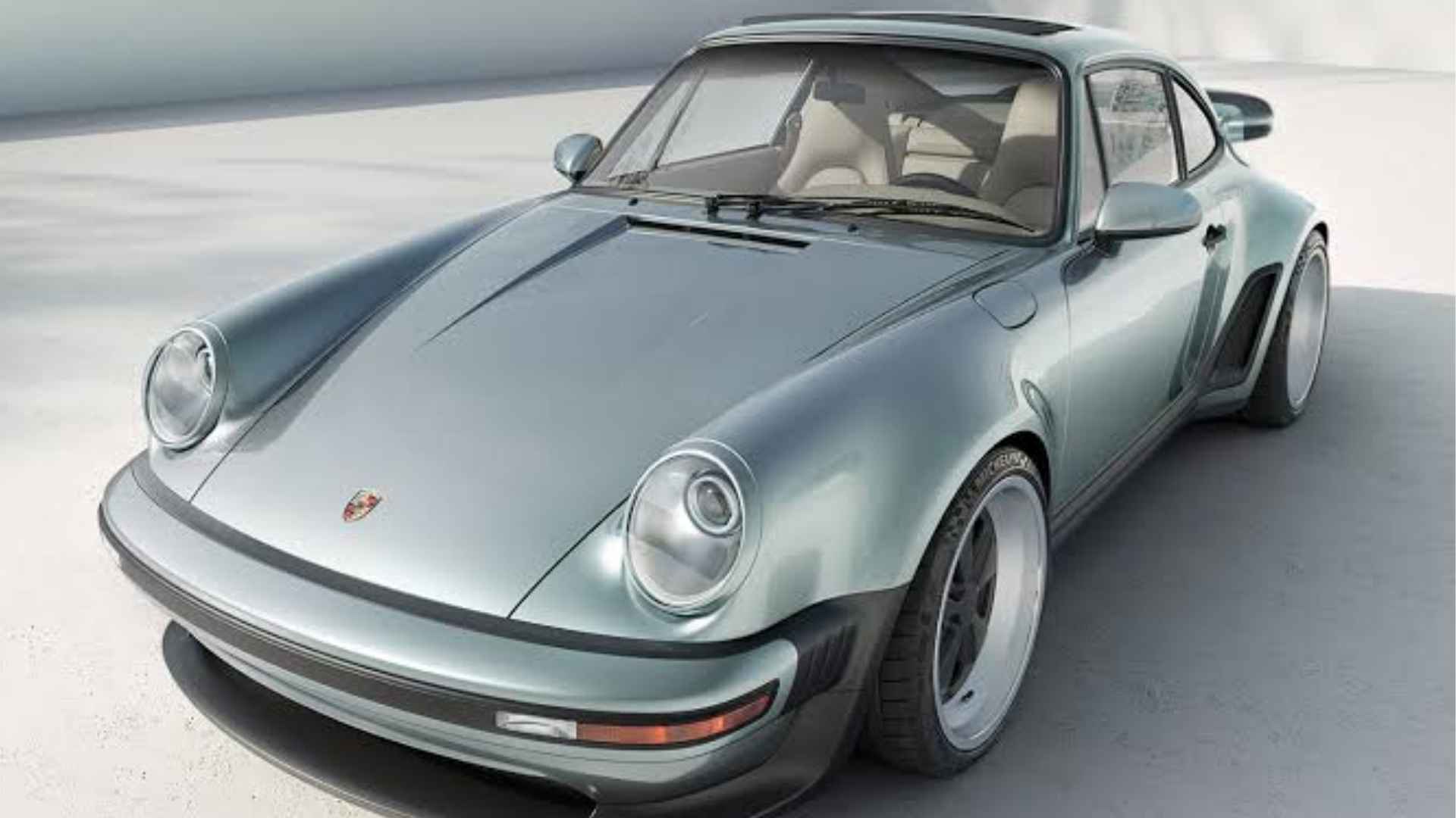 Light blue Singer Classic Turbo Porsche 911 with wide wheel arches and a cream interior in sunlight.