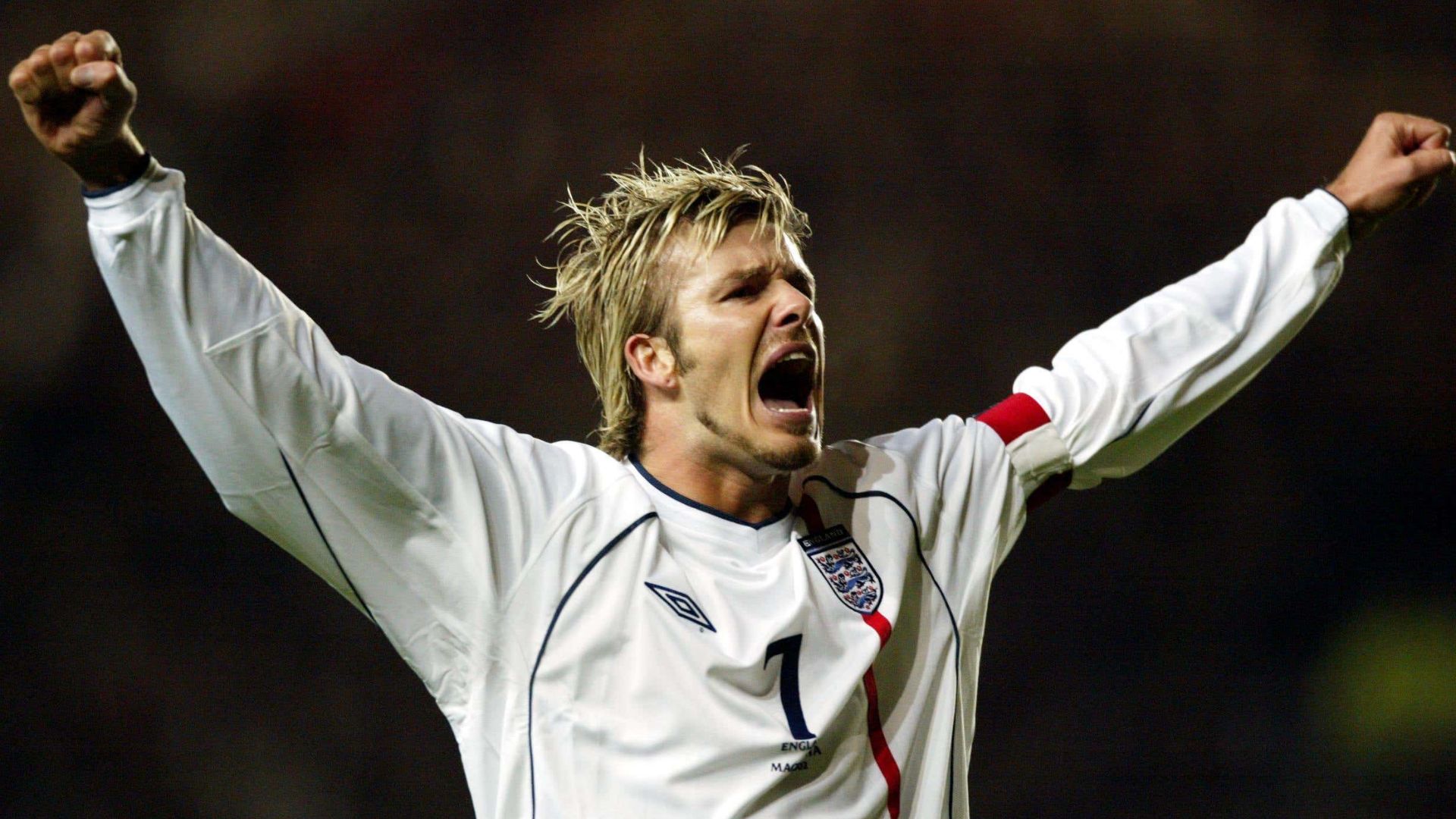 David Beckham celebrating with his arms raised while playing for England.