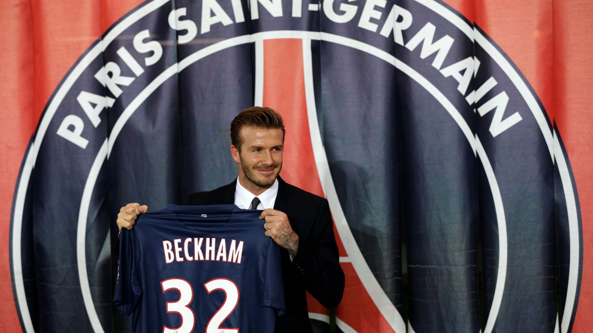 David Beckham holding his PSG jersey during his presentation at Paris Saint-Germain.
