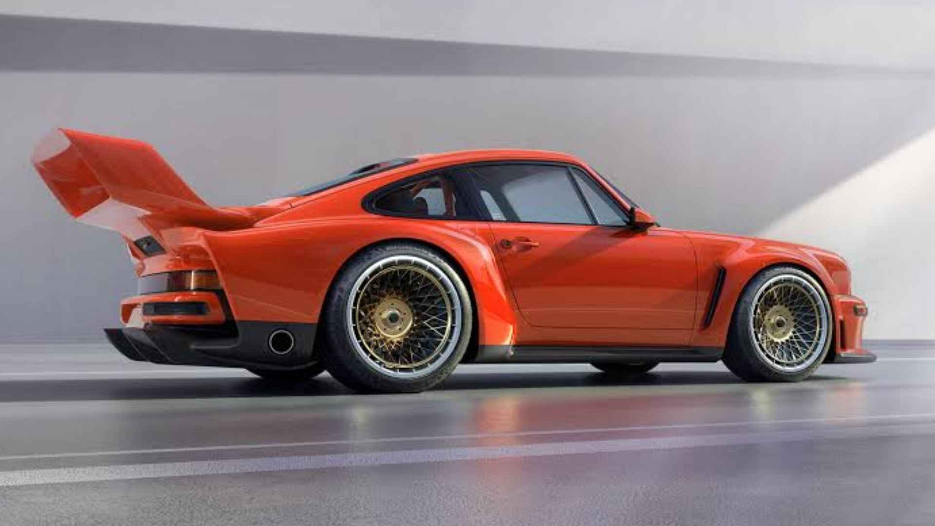 Orange Singer DLS Turbo Porsche 911 with a large rear wing and gold wheels in a gray studio setting.