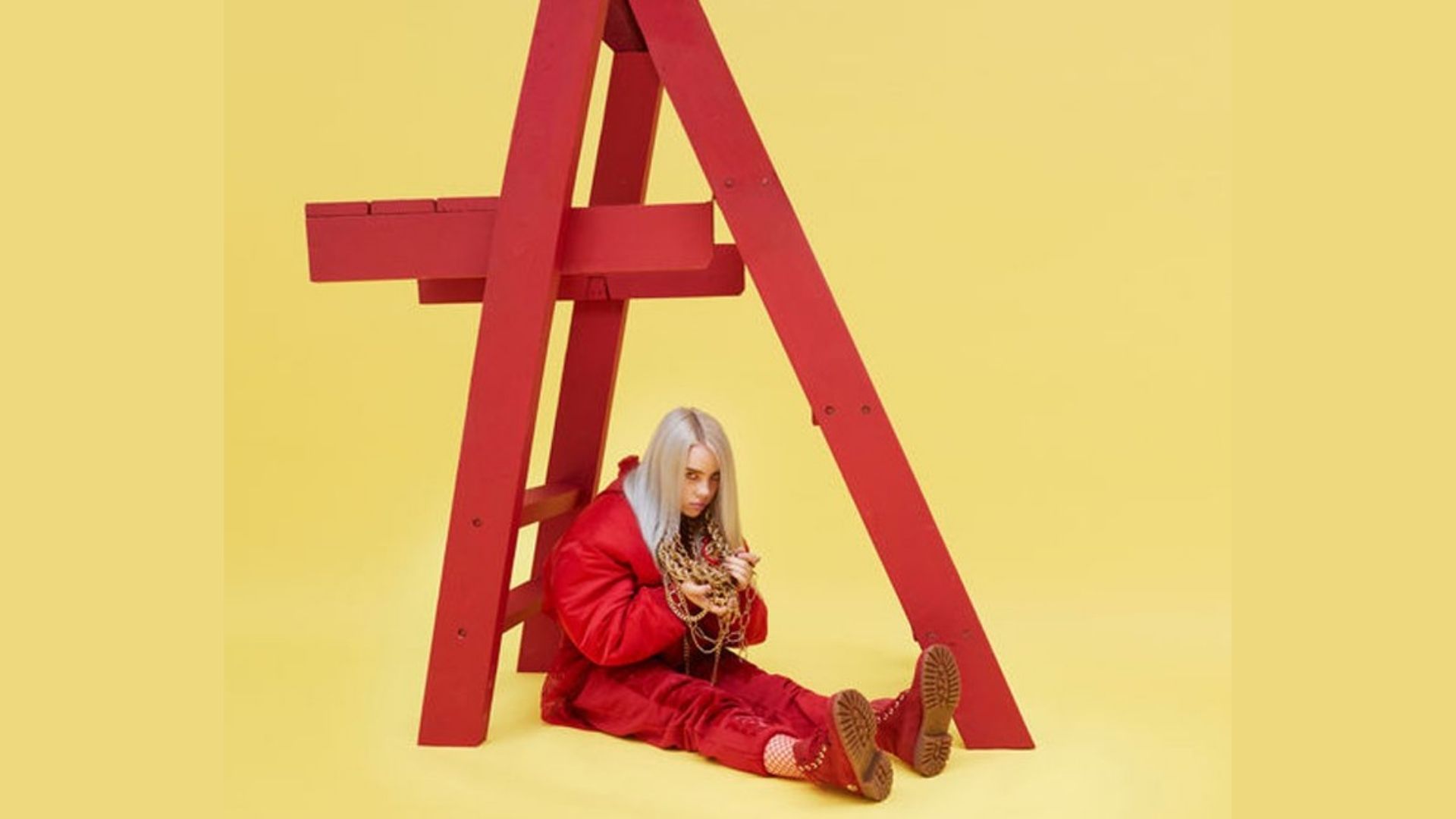 Album cover for Billie Eilish’s “don't smile at me,” showing the silver-haired artist sitting beneath a red wooden ladder against a bright yellow background.