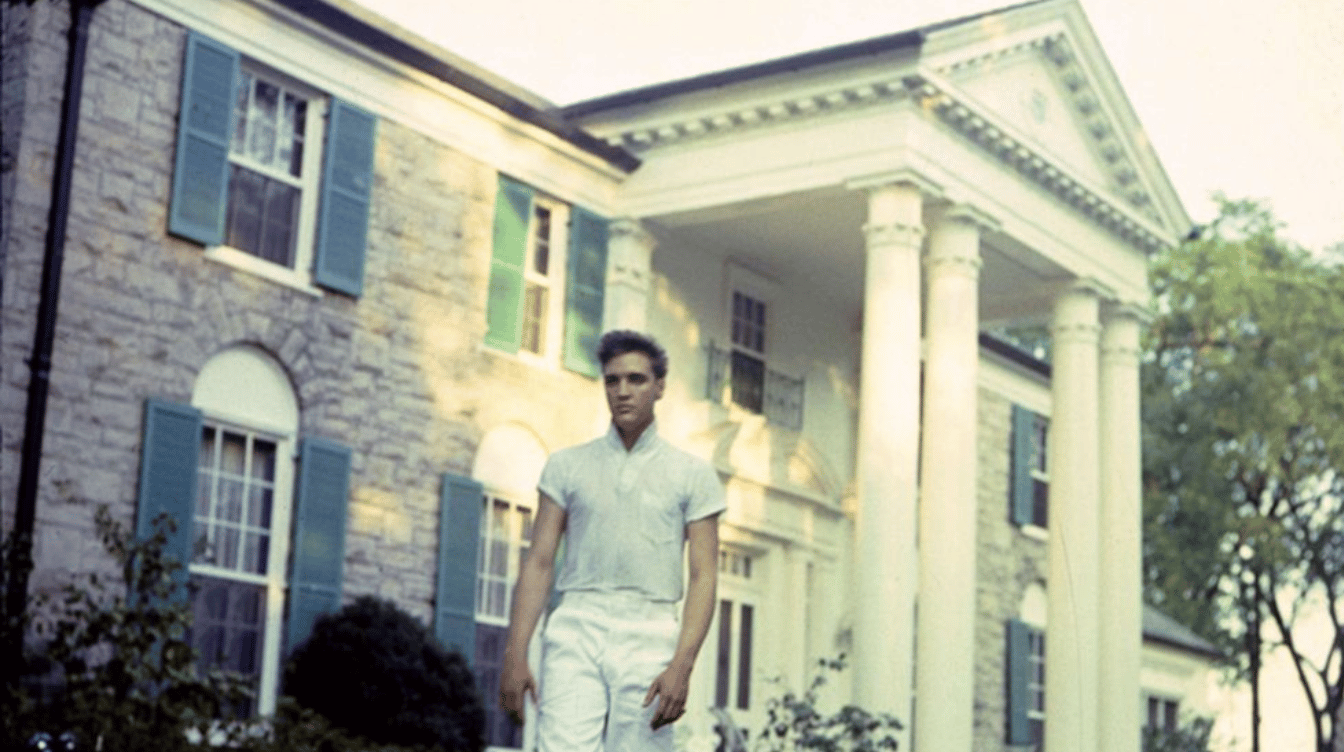 young elvis presley standing outside graceland mansion during his early career