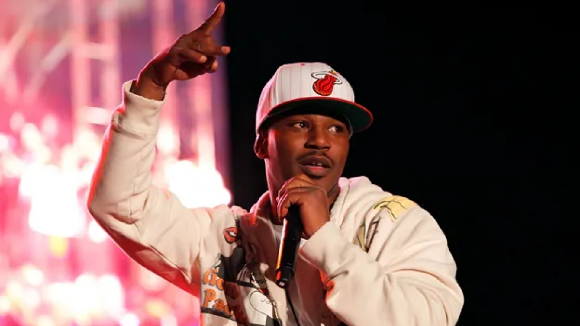 Cam'ron in a white printed hoodie and cap performing on stage