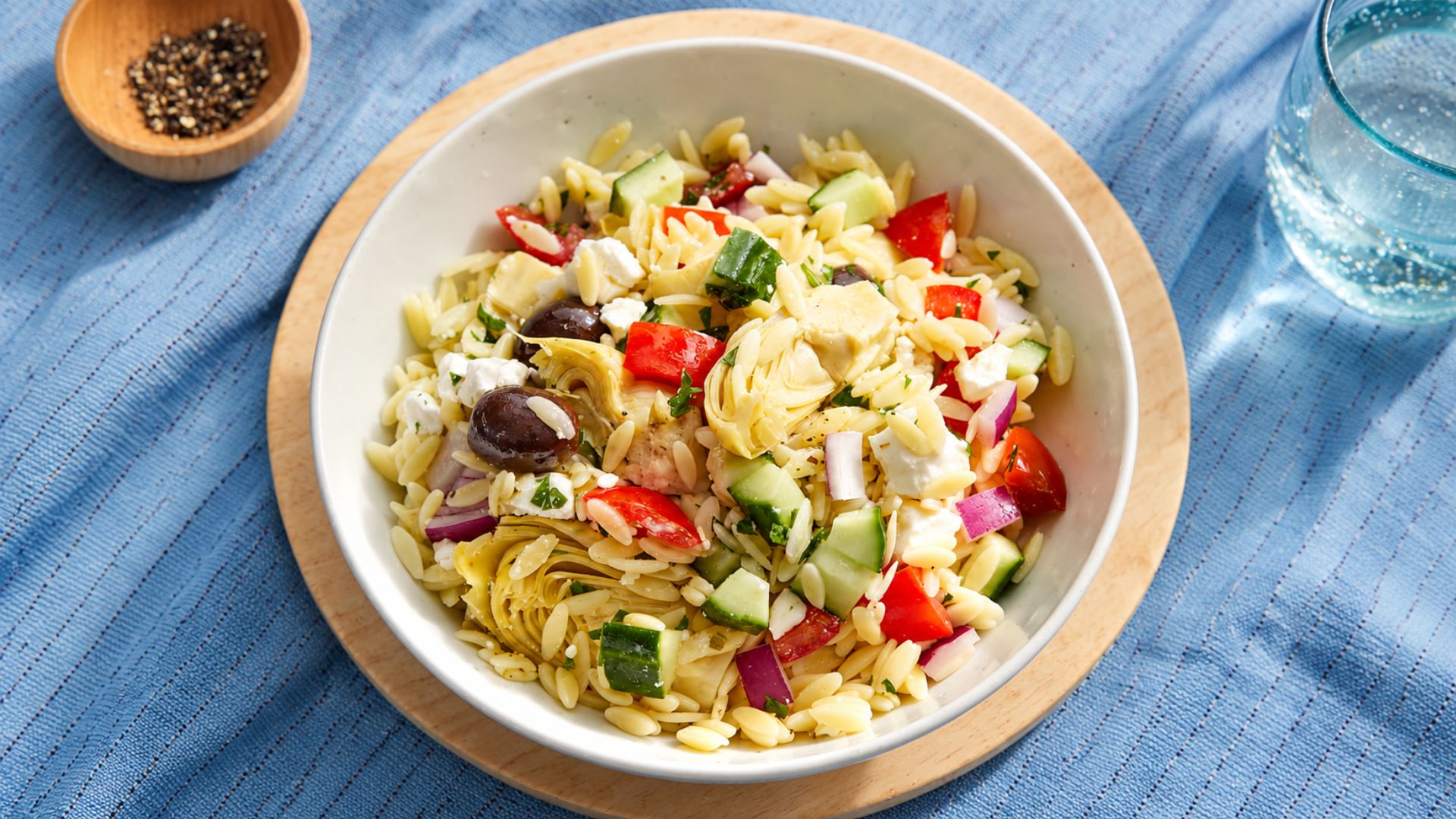 Greek orzo salad with chickpeas, cucumber, tomatoes, olives, feta, parsley and lemon.