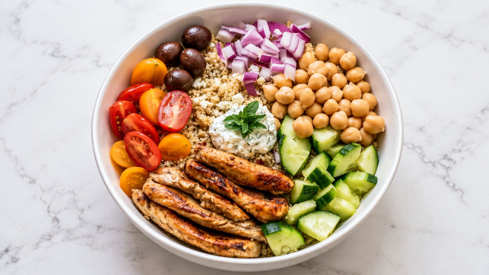 Greek chicken grain bowl with grilled chicken, quinoa, cucumber, tomatoes, olives and feta.