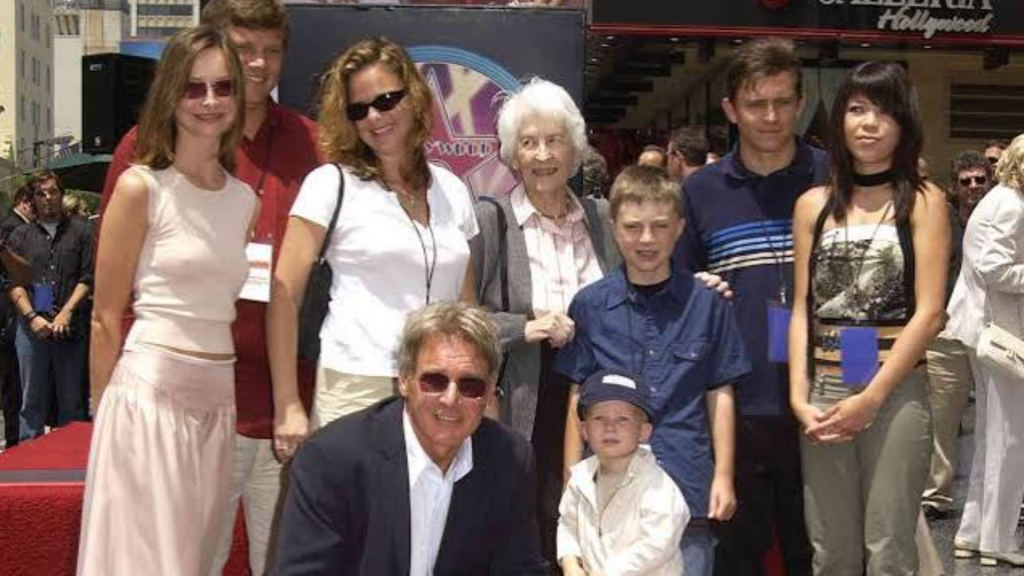 harrison ford and his family posing at hollywood event with his wife and children gathered around harrison ford in sunglasses on red carpet
