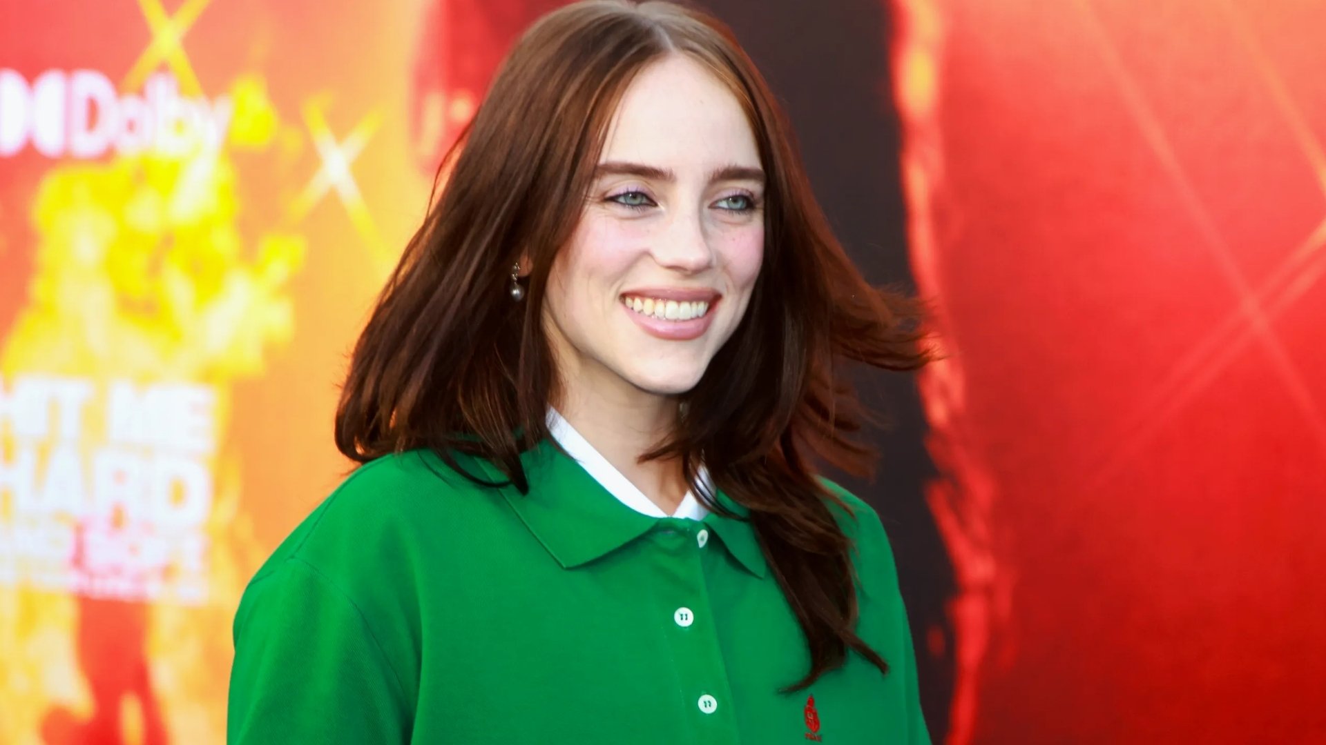 Billie Eilish wearing a vibrant green short-sleeve collared polo shirt on the red carpet.