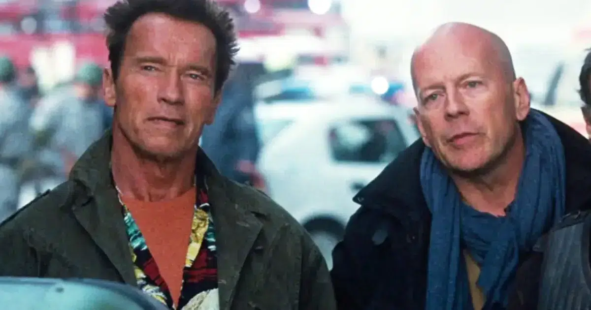 arnold schwarzenegger and bruce willis standing together in a film scene with vehicles behind them
