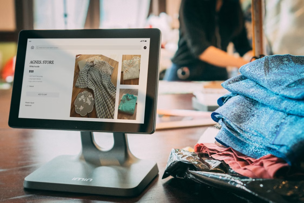 Touchscreen display showing online clothing store interface in a fabric shop setting