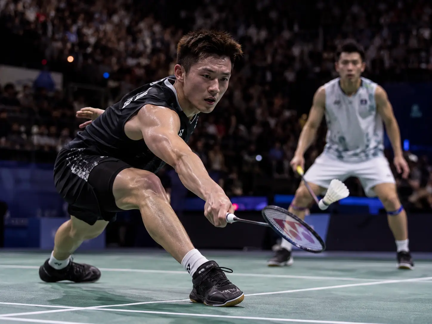 Badminton players in intense match on indoor court with a focused audience