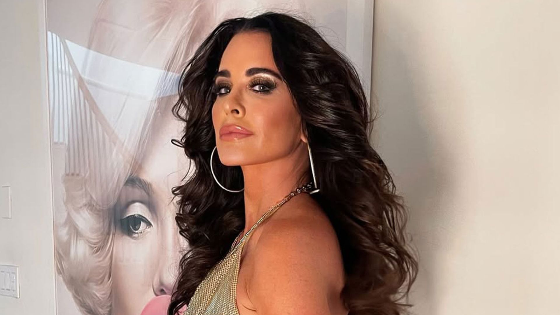 Kyle Richards posing in a gold outfit with voluminous waves while reflecting on her RHOBH future.