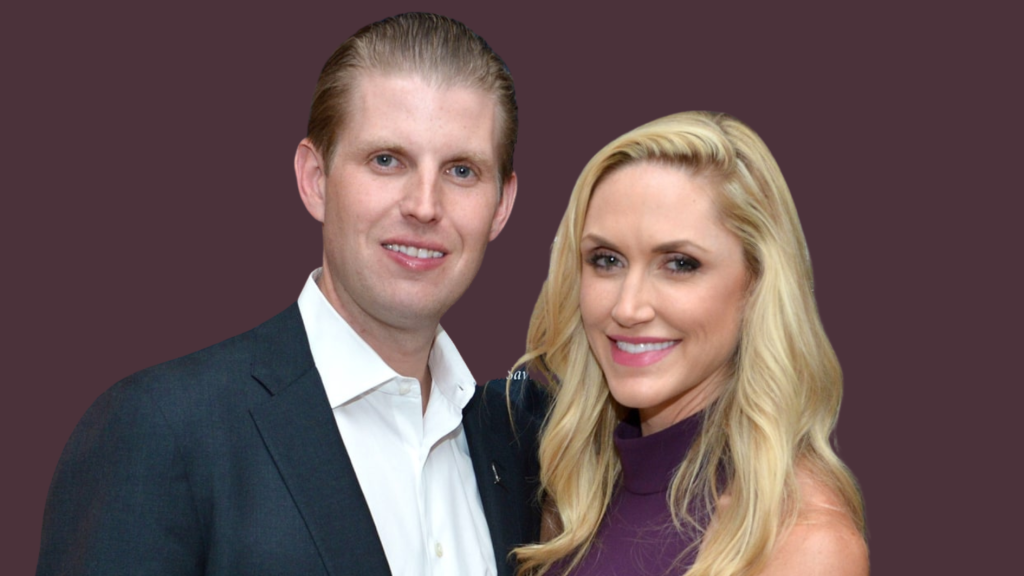 eric trump smiling in dark suit beside lara trump in purple outfit with maroon background