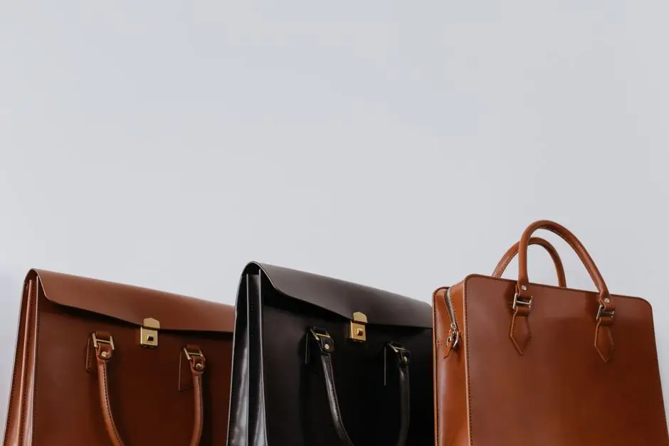 Three leather briefcases in brown and black set against a plain background