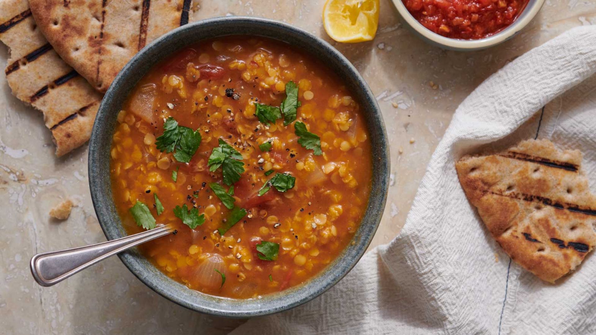 Hearty lentil soup with carrots, celery, tomatoes and spinach served warm in a ceramic bowl.