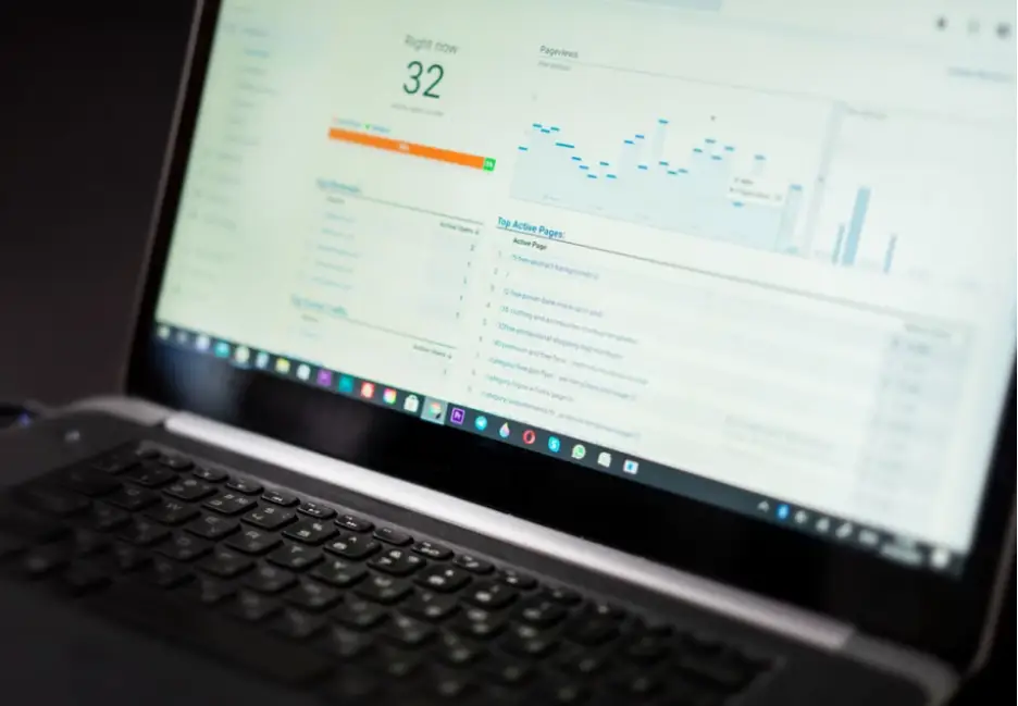Laptop displaying analytics data with charts and graphs in a dimly lit office setting