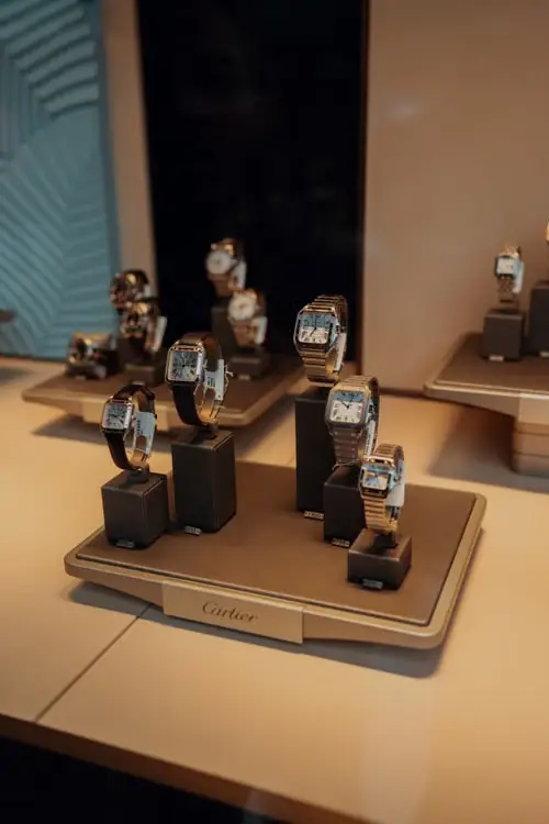 Luxury watches displayed on beige stands in well-lit jewelry store setting