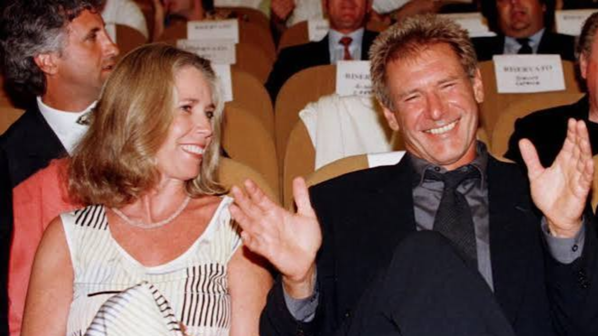 image of harrison ford and melissa mathison sitting and laughing together at a show