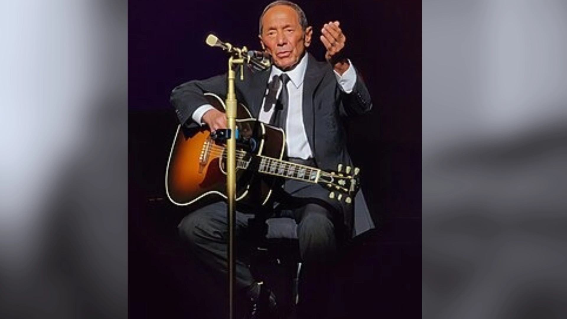 paul anka performing on stage while playing guitar and singing into a microphone