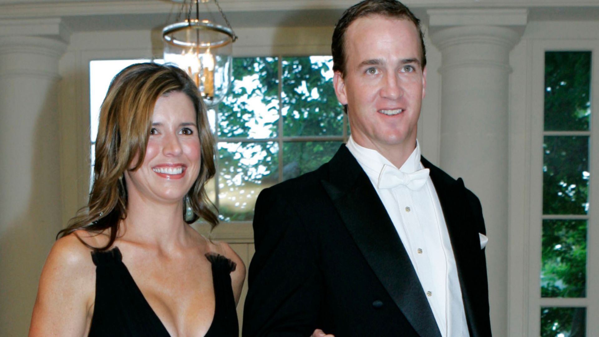 Peyton Manning and his wife Ashley Thompson posing together in formal attire at an indoor event.