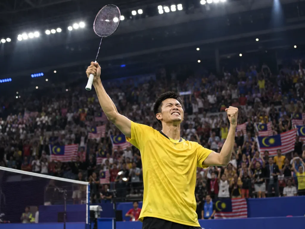 Badminton player in yellow shirt celebrating victory in crowded stadium with cheering fans