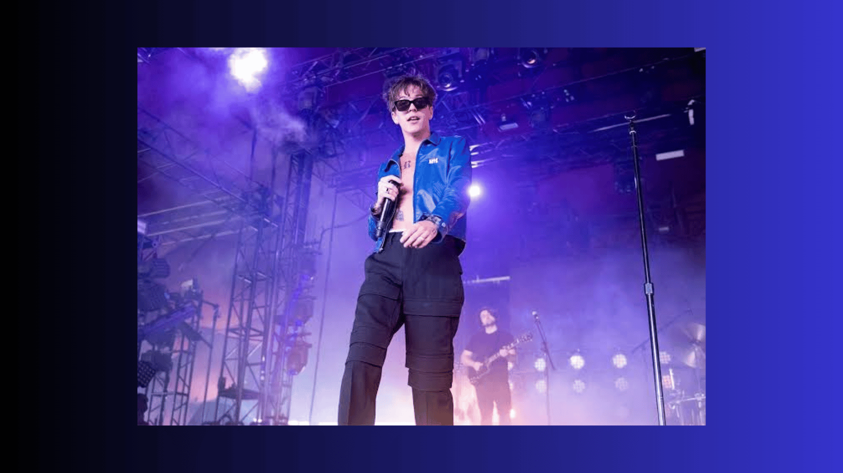 role model performing on stage in a blue jacket under purple lights