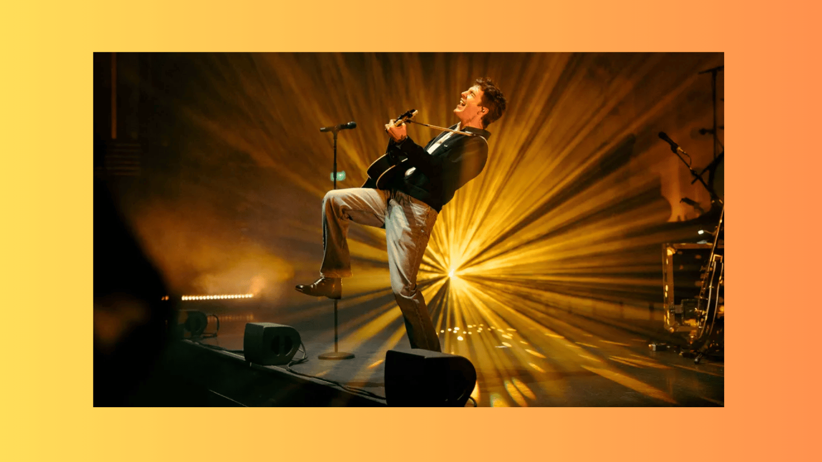 role model playing guitar during a live performance with golden stage lights
