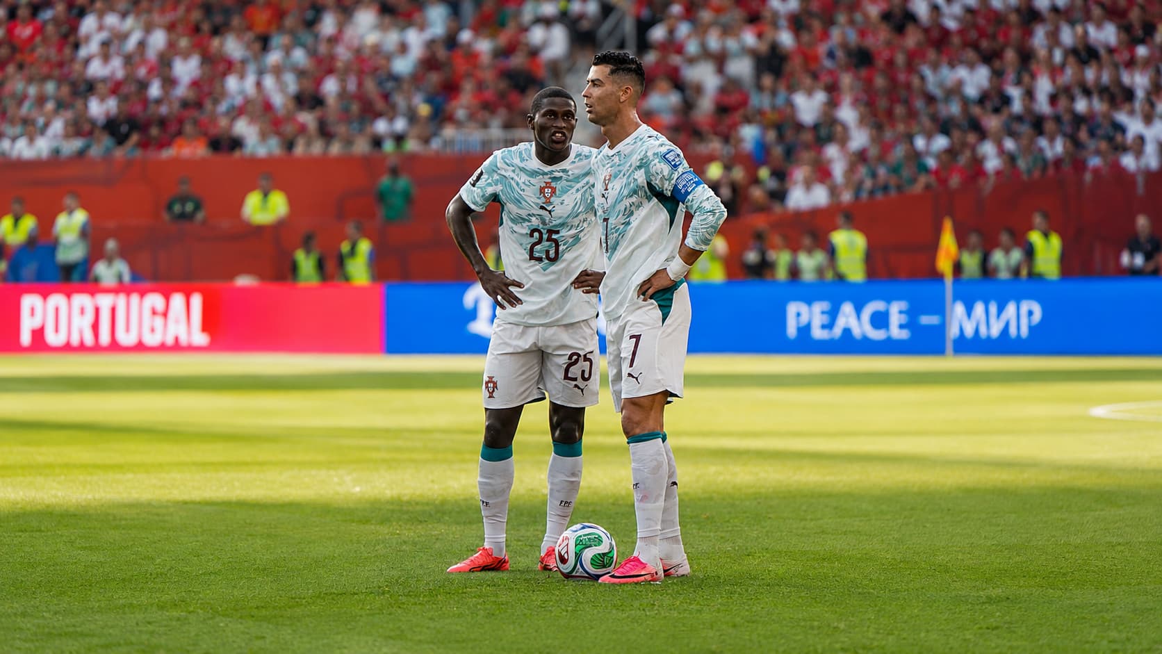 Cristiano Ronaldo and a Portugal teammate standing together on the football pitch during a match