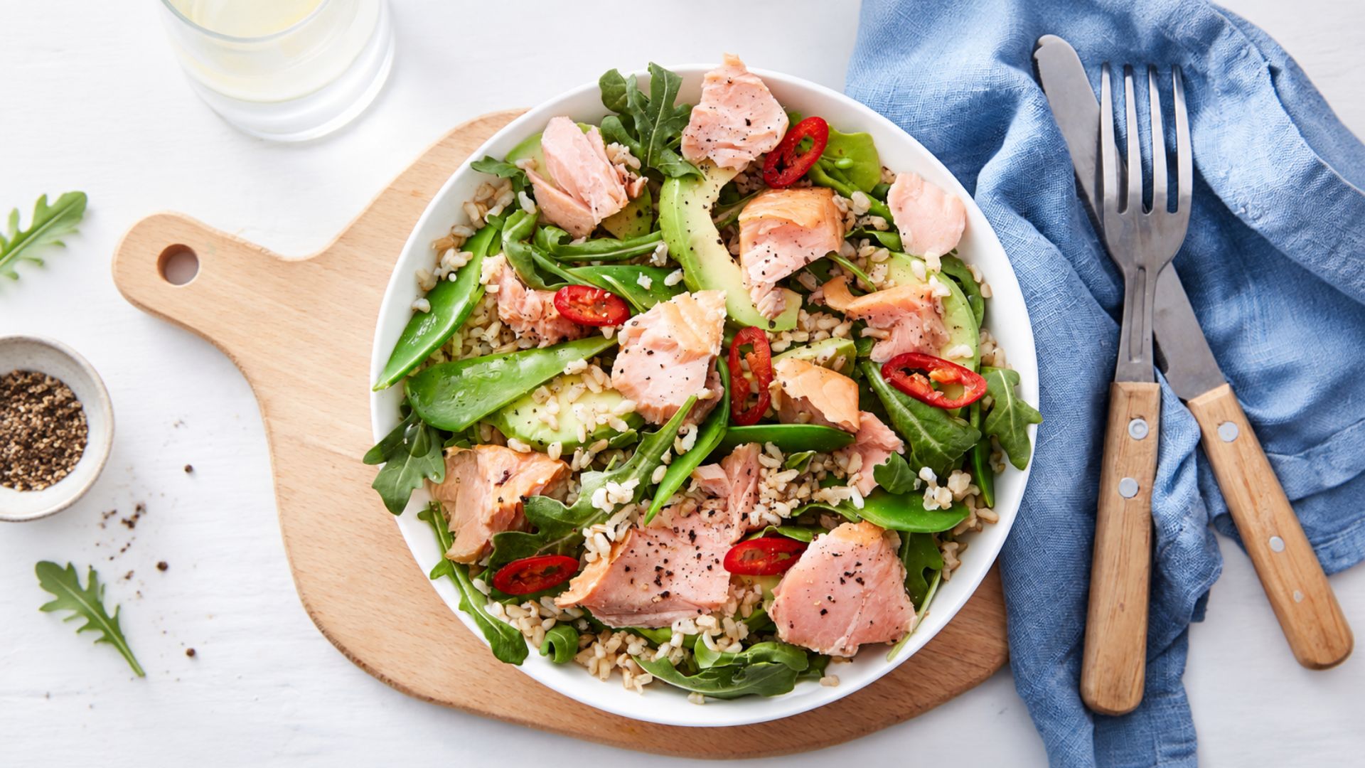 Salmon avocado salad with flaky cooked salmon, greens, cucumber, cherry tomatoes and ripe avocado.