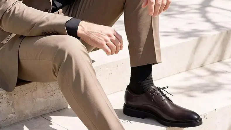 Man in tan suit sitting on stone steps wearing dark brown leather shoes