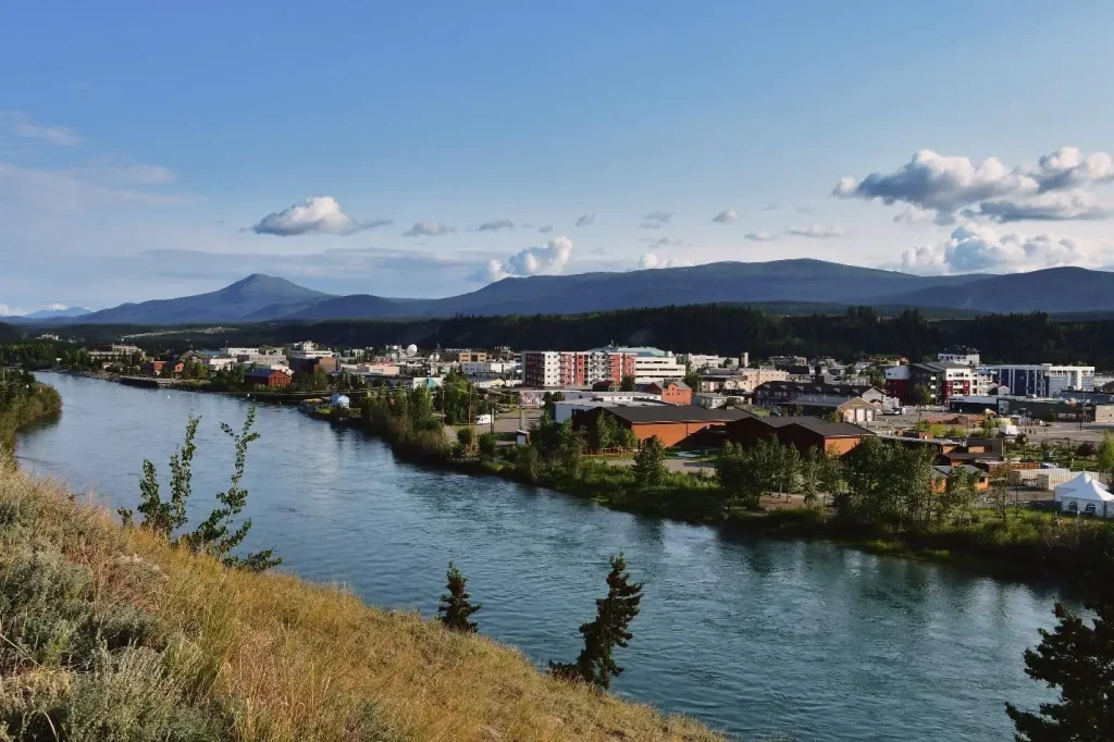 River flowing through a city with mountains in the background under a clear blue sky