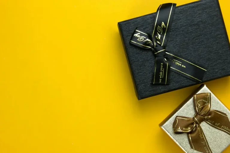 Black and gold gift boxes with ribbons on yellow background