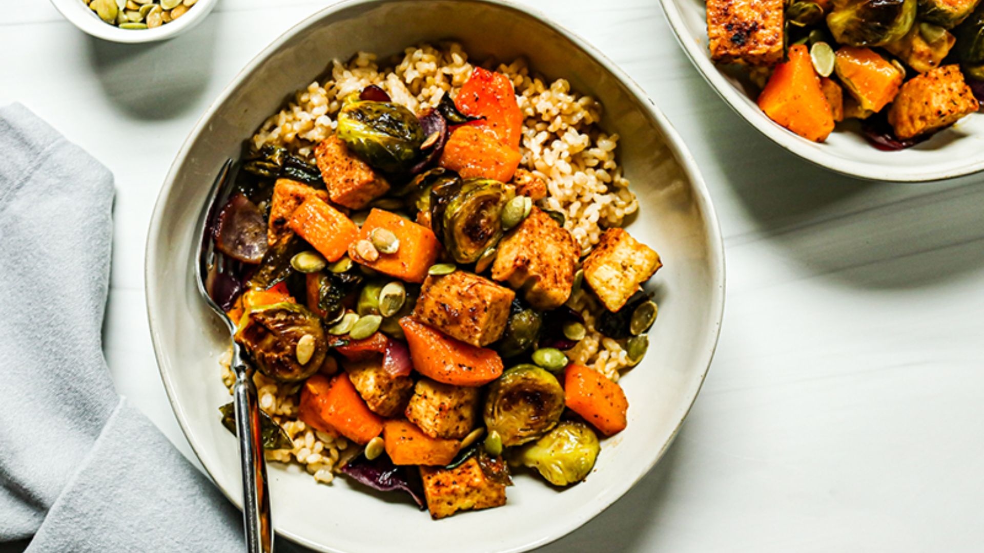 Tofu and roasted vegetable bowl with brown rice, broccoli, mushrooms, carrots and sesame seeds.