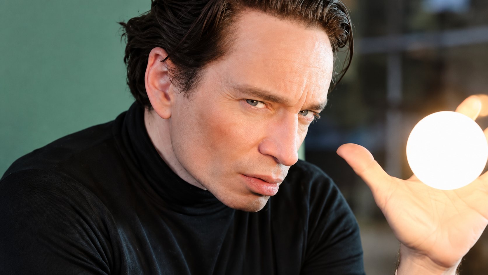 close up portrait of chris kattan in black turtleneck showing an intense expression with dramatic lighting and blurred background