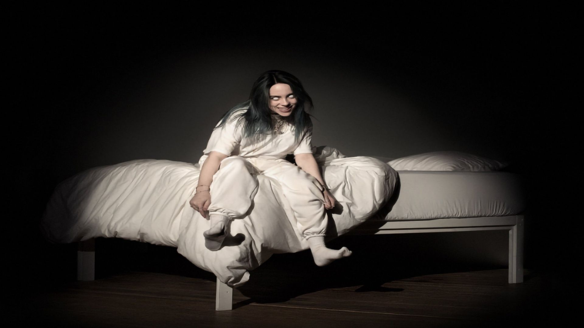 Album cover for Billie Eilish’s “When We All Fall Asleep, Where Do We Go?”, featuring the artist sitting on a glowing bed in a dark room with a wide grin and eerie, white eyes.