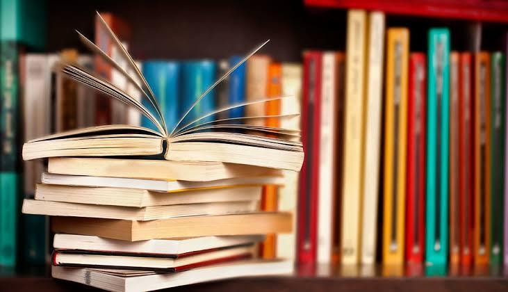 Open book on stack with colorful bookshelf background in a library setting