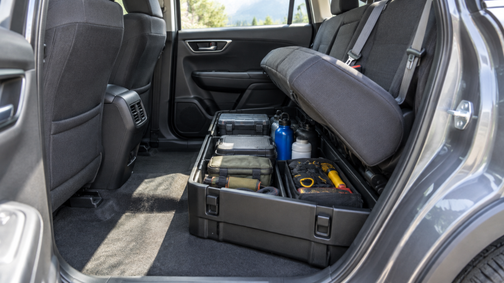 Car interior showing rear seat storage compartment with tools and water bottles stored inside