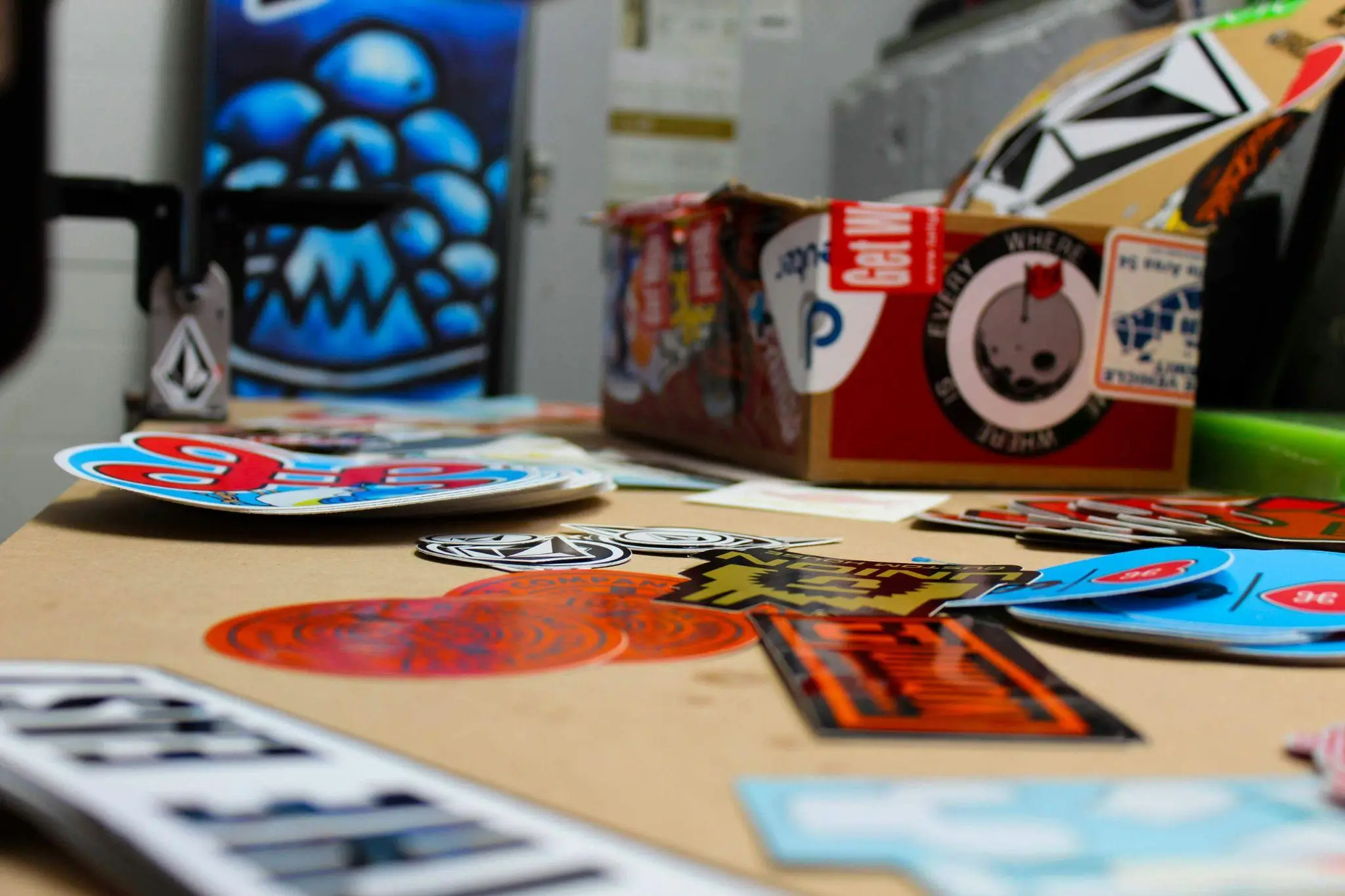 Assorted colorful stickers and a cardboard box on a table in a workshop setting