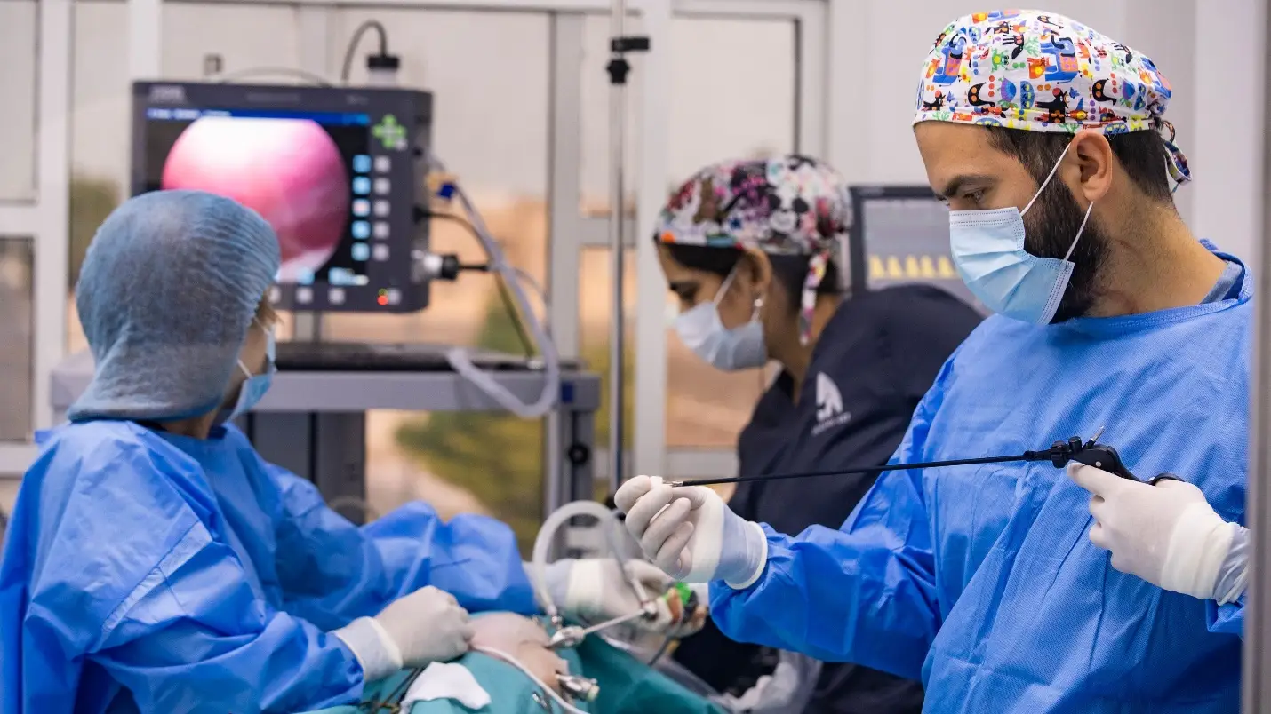 Surgical team performing endoscopic procedure in hospital operating room with monitors